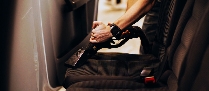 a person vacuuming seats of a car